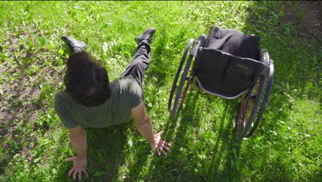 The-physically-disabled-young-man-lies-on-the-grass-and-leans-against-his-wheelchair.